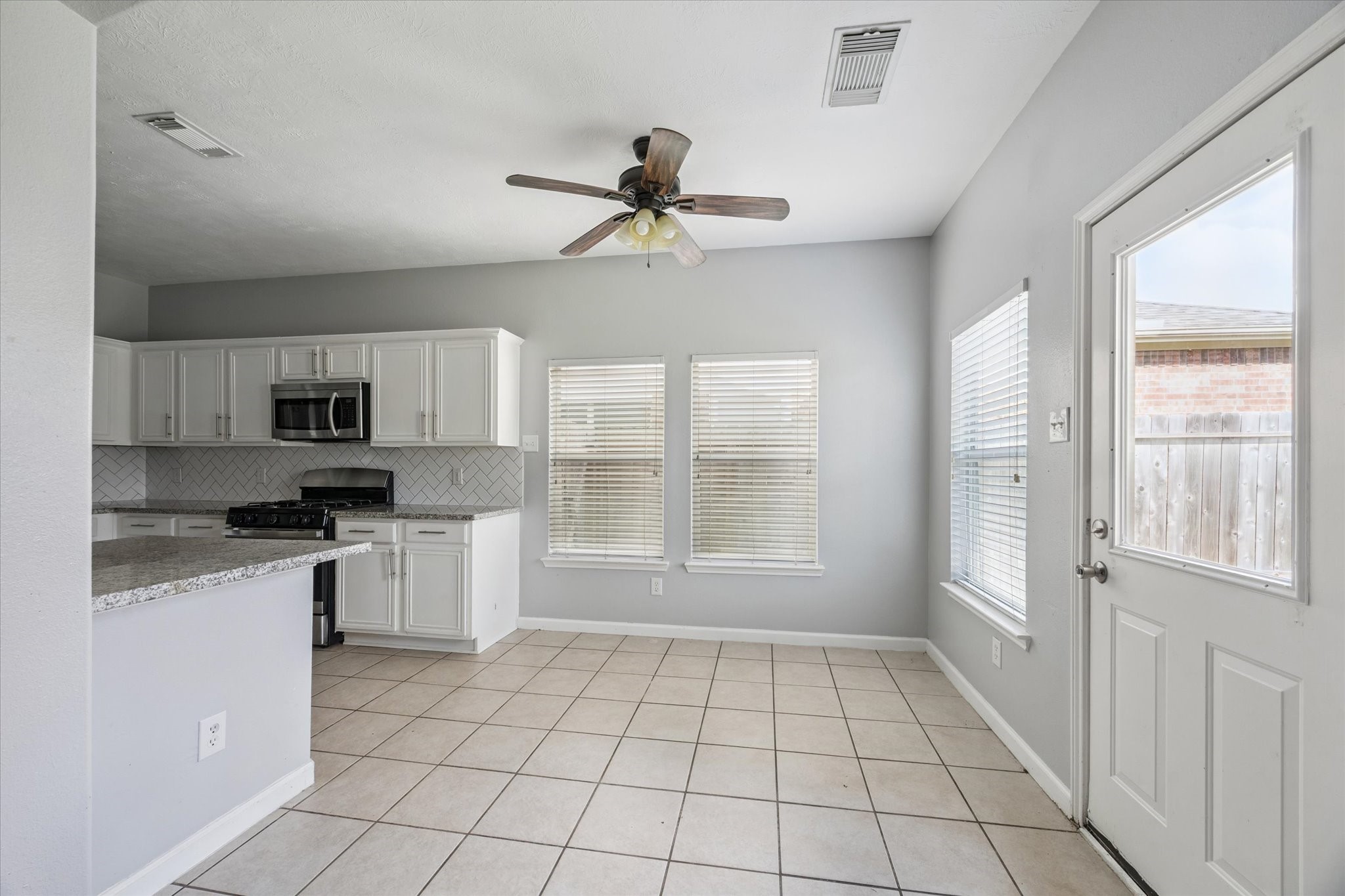 18239 Eton Ridge Court Richmond, TX 77407 - Photo 5 of 10 a kitchen with granite countertop a refrigerator a sink a stove a microwave and cabinets