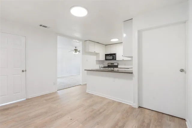 a kitchen with a refrigerator and white cabinets