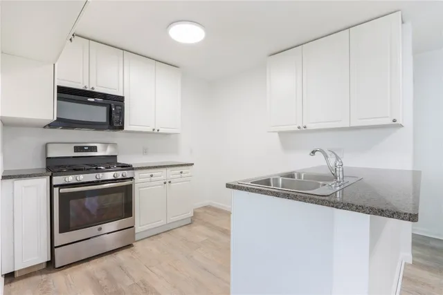 a kitchen with stainless steel appliances granite countertop a sink stove a microwave and cabinets