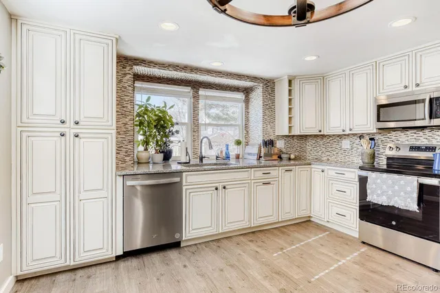 a kitchen with stainless steel appliances granite countertop a stove a sink and a refrigerator