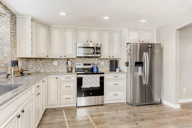a kitchen with white cabinets and stainless steel appliances