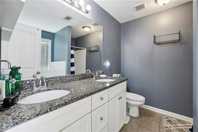 a bathroom with a granite countertop sink a toilet and a mirror