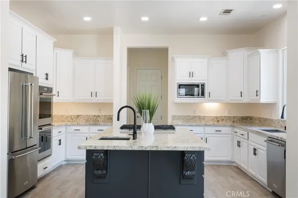 a kitchen with kitchen island granite countertop a sink and white cabinets