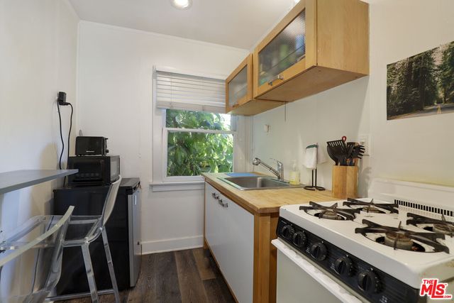 a kitchen with a stove a sink and wooden floor