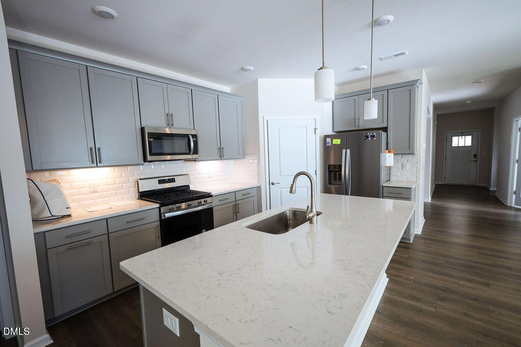 1644 Abberly Place Graham, NC 27253 - Photo 13 of 33 a kitchen with granite countertop a refrigerator a sink dishwasher stove top oven a dining table and chairs with wooden floor