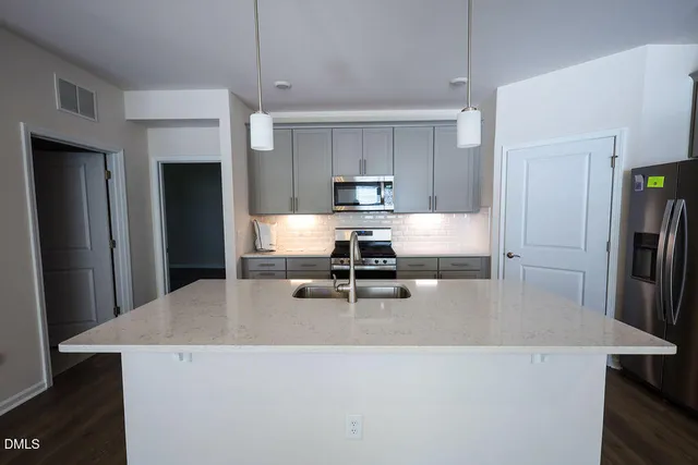 a living room with stainless steel appliances a dining table chairs refrigerator and kitchen view