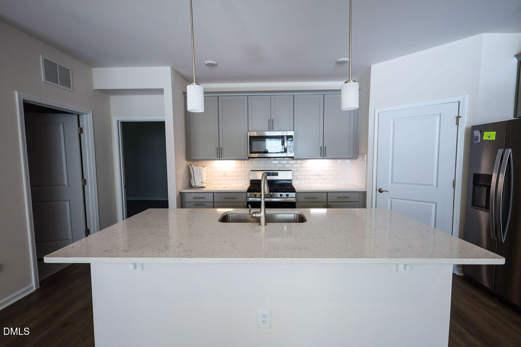 1644 Abberly Place Graham, NC 27253 - Photo 15 of 33 a living room with stainless steel appliances a dining table chairs refrigerator and kitchen view
