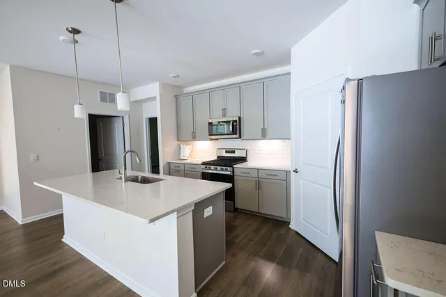 a kitchen that has a refrigerator a stove and a sink with wooden floor