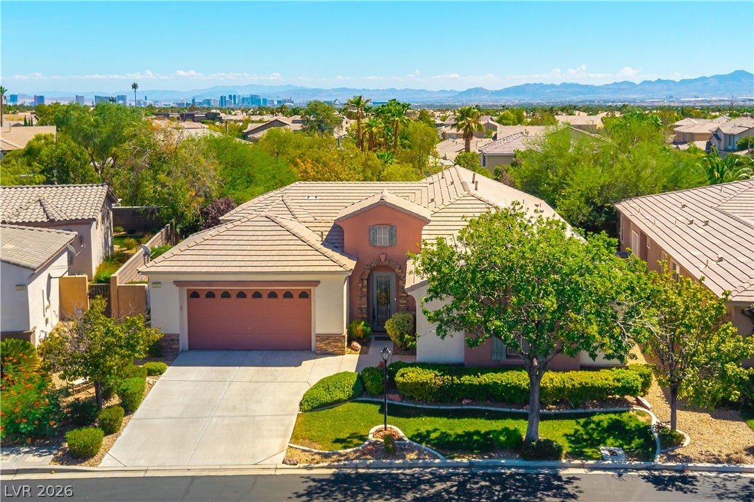 3334 Garden Shower Place Las Vegas, NV 89135 - Photo 24 of 32 An inviting exterior with a tile roof and manicured lawn enjoys distant city skyline views.