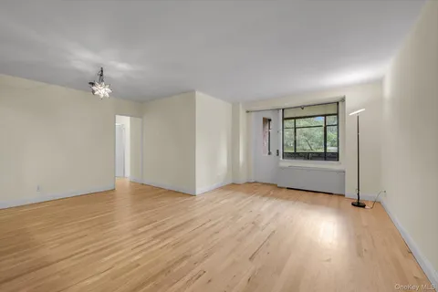 an empty room with wooden floor chandelier fan and windows