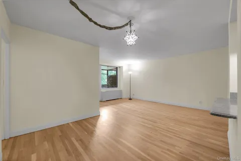 an empty room with wooden floor chandelier and windows