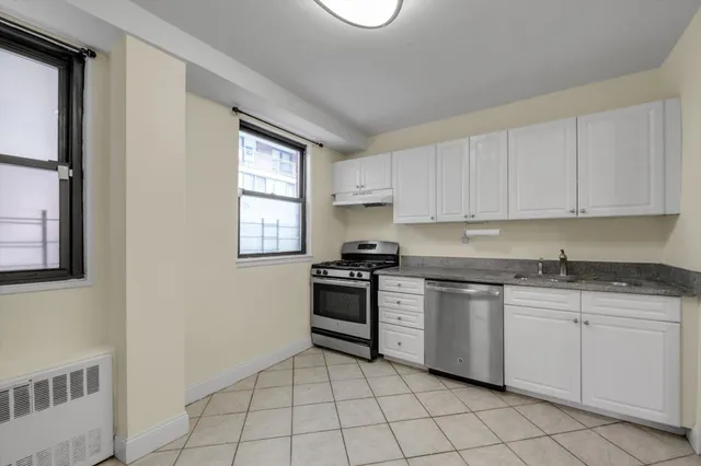 a kitchen with white cabinets appliances and a window
