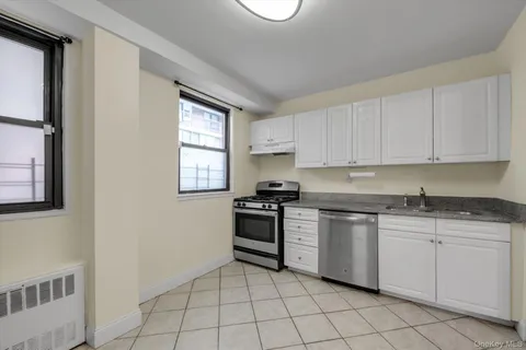 a kitchen with white cabinets appliances and a window