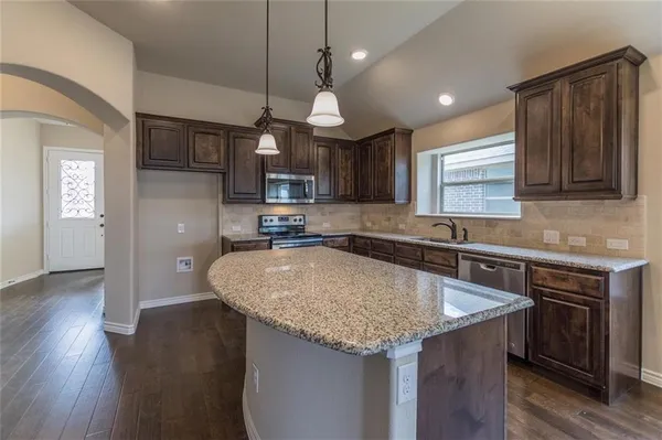 a kitchen with stainless steel appliances granite countertop a sink a stove and a wooden floors