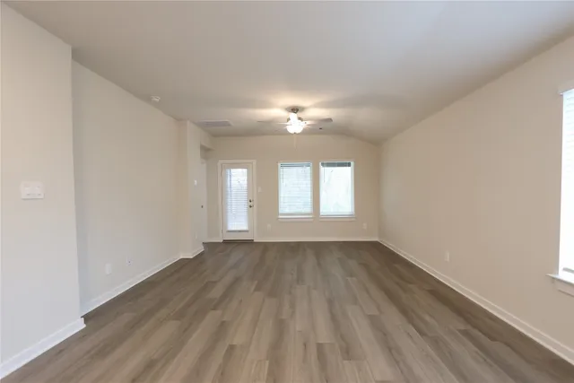 a view of an empty room with wooden floor and a window