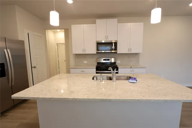 a kitchen with stainless steel appliances a sink a stove a refrigerator and cabinets