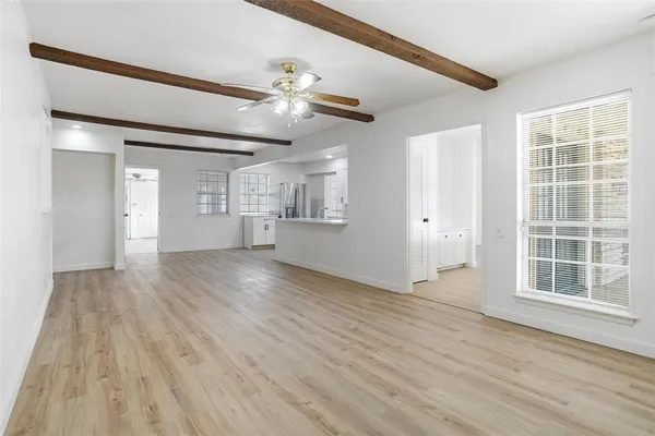 a view of an empty room with a window and wooden floor