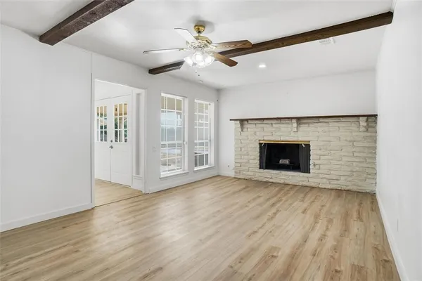 a view of an empty room with wooden floor fireplace and a window
