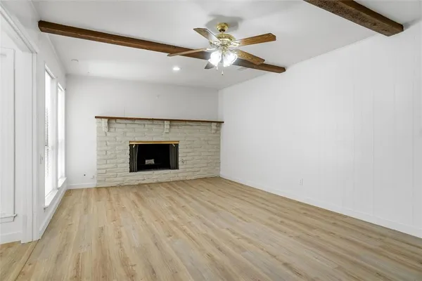 a view of an empty room with wooden floor and a fireplace