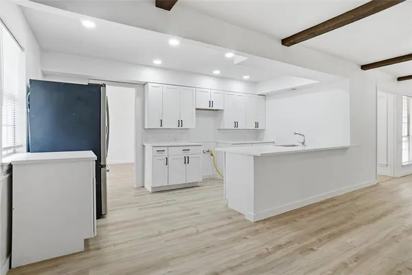 a large kitchen with stainless steel appliances granite countertop a white cabinets and a refrigerator