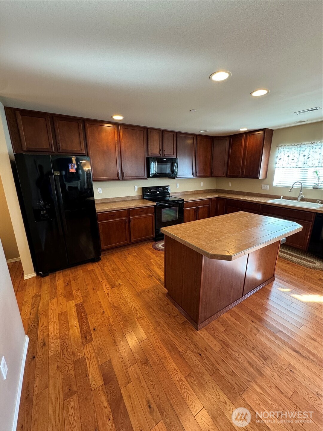 1175 Swan Loop DuPont, WA 98327 - Photo 6 of 34 a kitchen with stainless steel appliances kitchen island granite countertop a table chairs in it and wooden floors