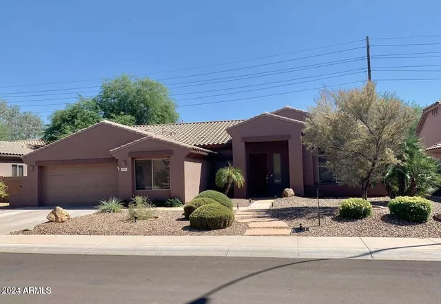 a front view of a house with a yard and potted plants