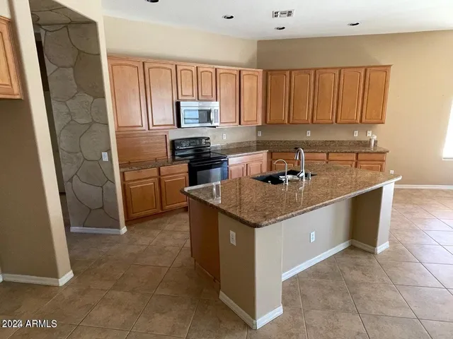 a kitchen with stainless steel appliances granite countertop a stove a sink and a refrigerator