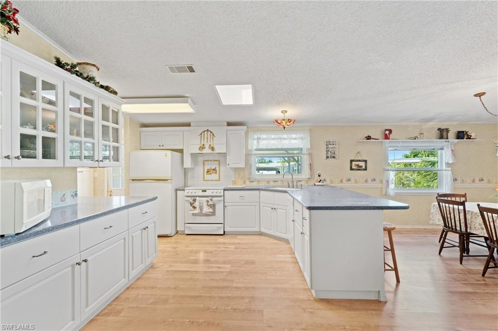 278 Riverwood Road Naples, FL 34114 - Photo 1 of 43 Kitchen with white appliances, light wood-type flooring, a peninsula, and a sink