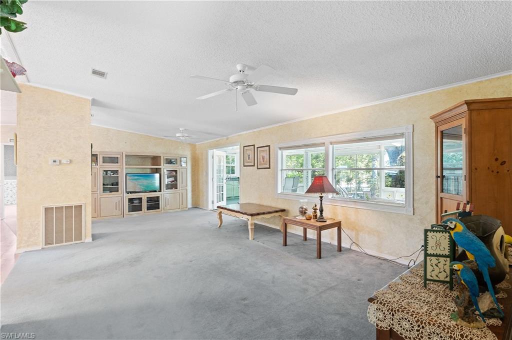 278 Riverwood Road Naples, FL 34114 - Photo 12 of 43 Carpeted living area with visible vents, lofted ceiling, a textured ceiling, and ceiling fan