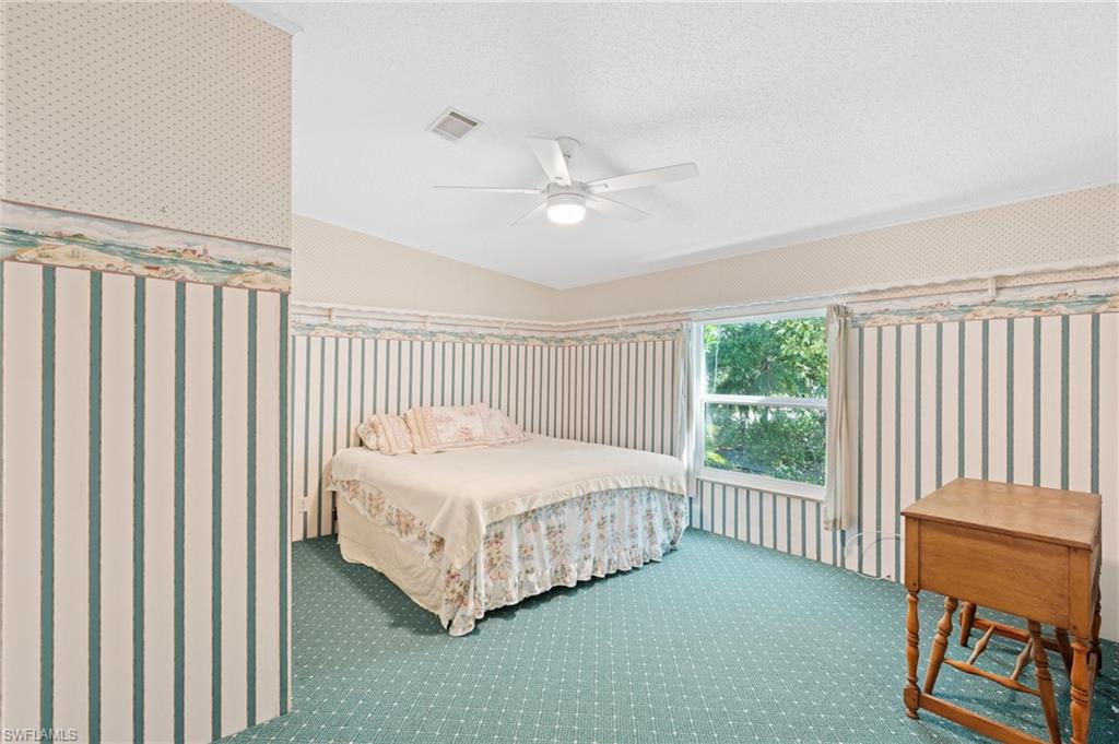 278 Riverwood Road Naples, FL 34114 - Photo 16 of 43 Bedroom with visible vents, a textured ceiling, carpet flooring, wallpapered walls, and ceiling fan