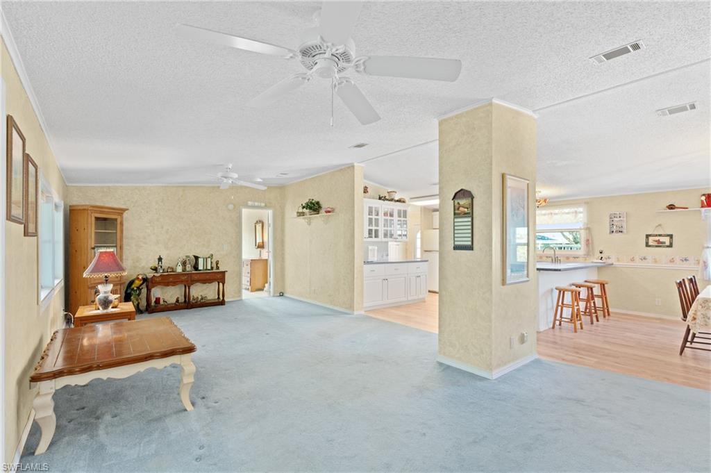 278 Riverwood Road Naples, FL 34114 - Photo 2 of 43 Carpeted living room with a sink, visible vents, a textured ceiling, and a ceiling fan