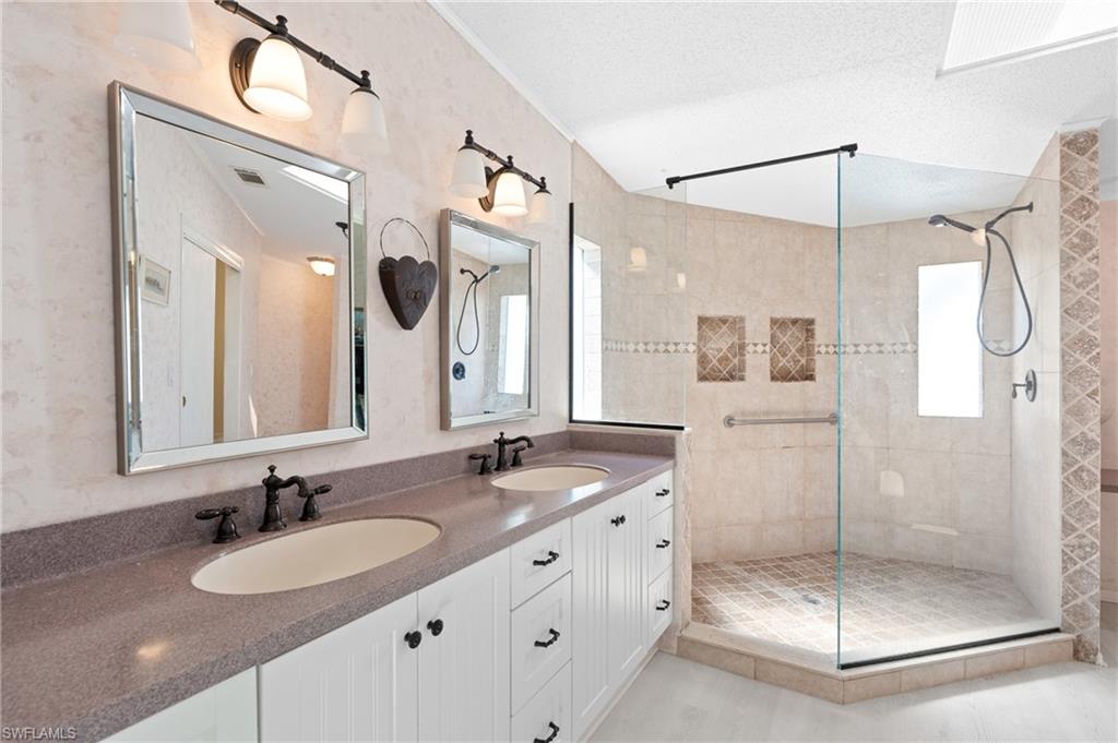278 Riverwood Road Naples, FL 34114 - Photo 21 of 43 Bathroom with a textured ceiling, tiled shower, and a sink