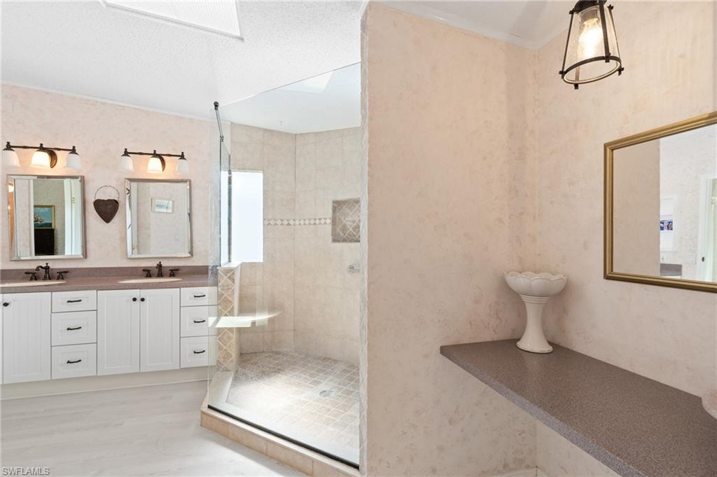 278 Riverwood Road Naples, FL 34114 - Photo 22 of 43 Bathroom featuring a tile shower, double vanity, a skylight, and a sink