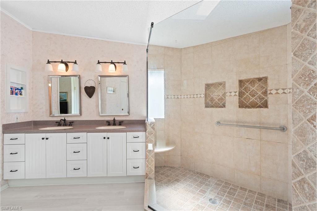 278 Riverwood Road Naples, FL 34114 - Photo 23 of 43 Full bath with double vanity, crown molding, a tile shower, and a sink