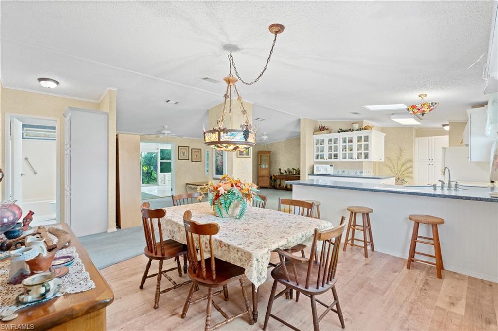 278 Riverwood Road Naples, FL 34114 - Photo 7 of 43 Dining area with a textured ceiling, a skylight, and light wood finished floors
