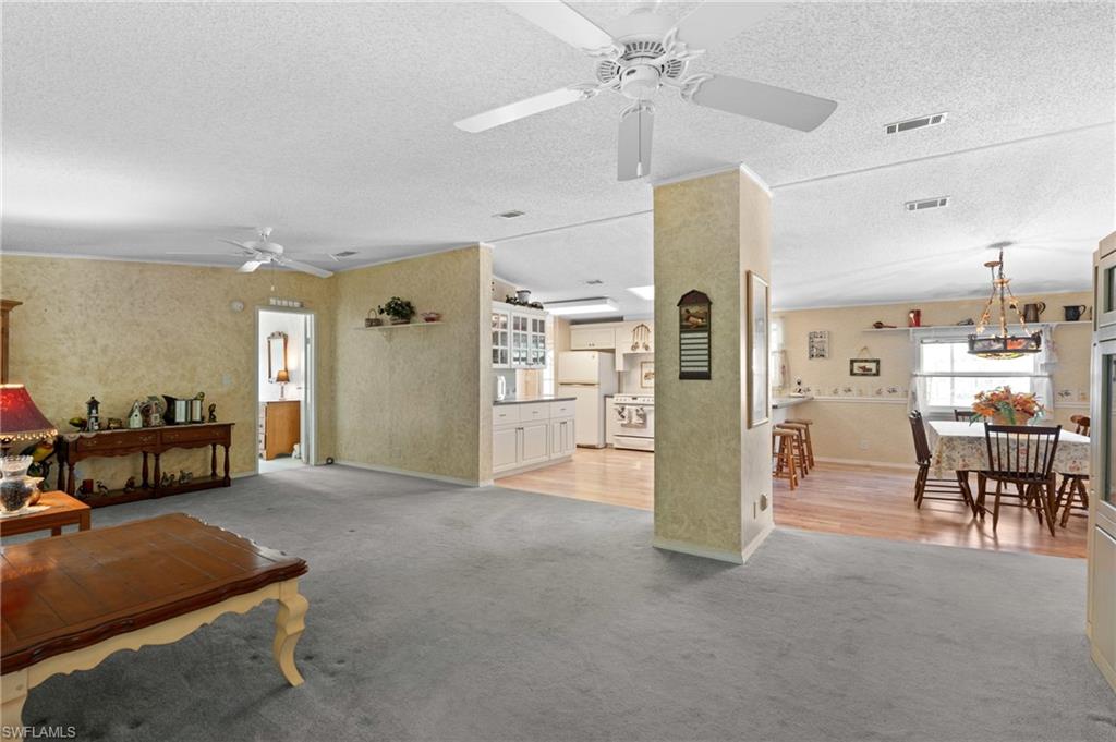 278 Riverwood Road Naples, FL 34114 - Photo 10 of 43 Living room featuring light carpet, visible vents, and a ceiling fan