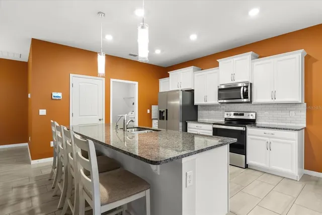 a large kitchen with stainless steel appliances granite countertop a sink and a refrigerator