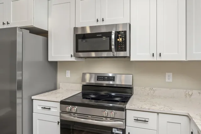 a kitchen with granite countertop white cabinets and stainless steel appliances