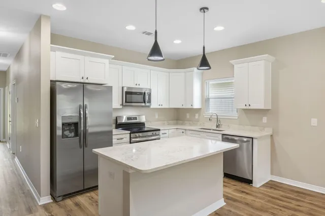a kitchen with a sink a center island a refrigerator and cabinets