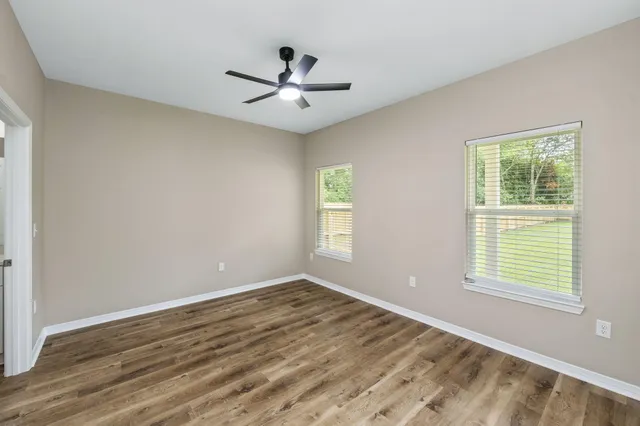 a view of empty room with wooden floor and fan