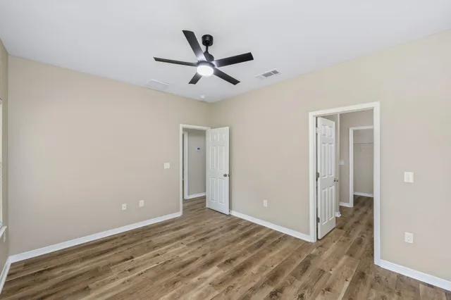 a view of a big room with wooden floor a ceiling fan
