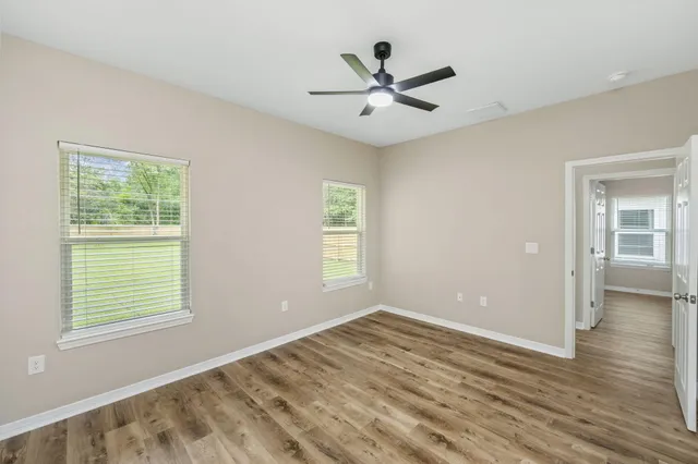 a view of a big room with wooden floor and windows
