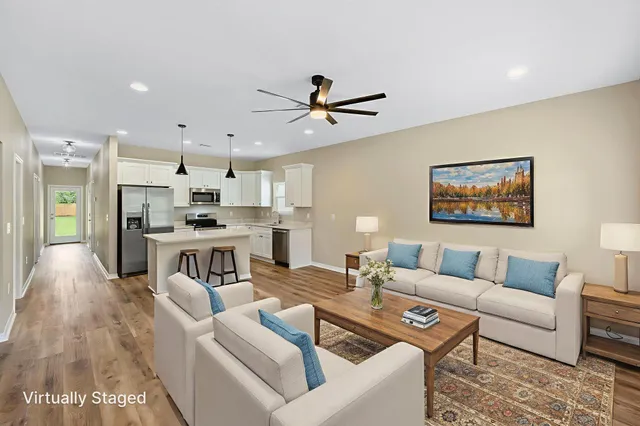 a living room with furniture kitchen view and a chandelier