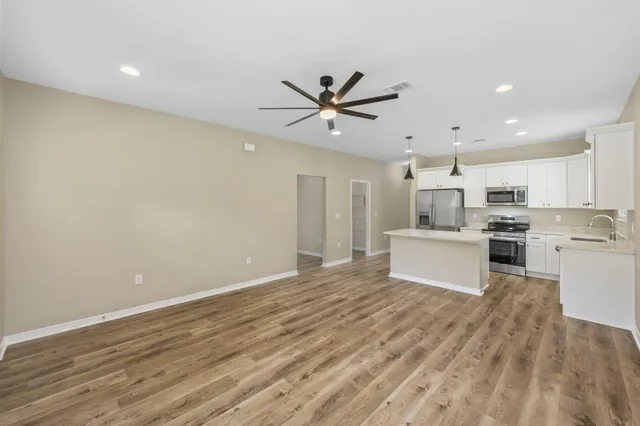 a view of a kitchen with a sink and dishwasher a refrigerator with wooden floor