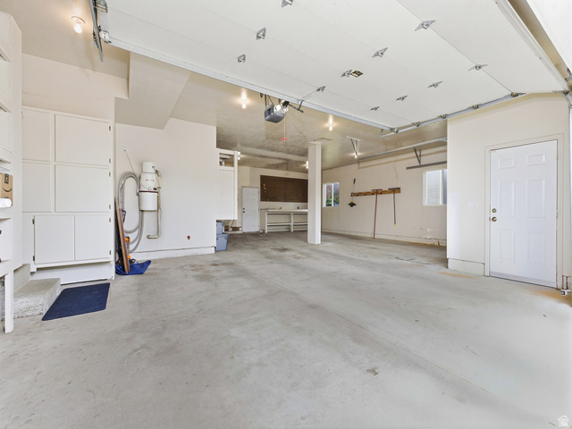 6849 North Black Powder Road Mountain Green, UT 84050 - Photo 38 of 43 Spacious garage with light-toned concrete flooring, overhead lighting, windows, built-in cabinetry, and a service door
