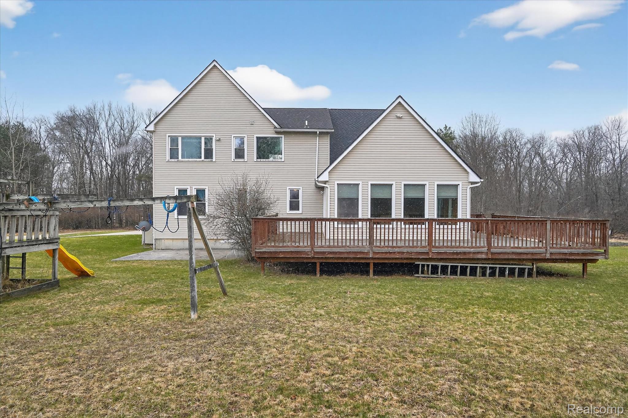 5640 Fisher Road Howell, MI 48855 - Photo 47 of 66 Rear view of property featuring a deck, a lawn, and a playground