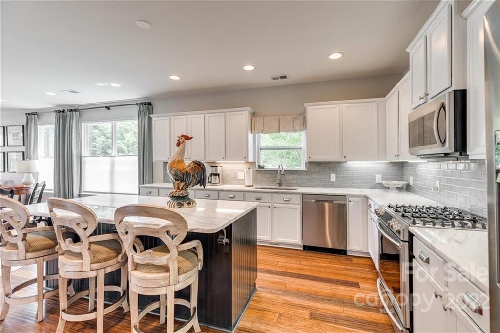 1007 Kaiser Way Fort Mill, SC 29715 - Photo 12 of 48 a kitchen with stainless steel appliances granite countertop a stove a sink dishwasher a microwave oven with a dining table and chairs