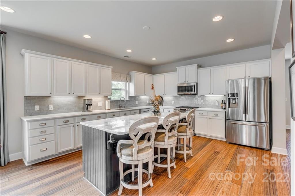 1007 Kaiser Way Fort Mill, SC 29715 - Photo 10 of 48 a kitchen with stainless steel appliances granite countertop a stove top oven a sink dishwasher a refrigerator and white cabinets with wooden floor