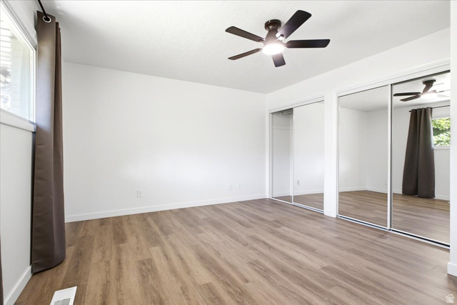 1676 East 11245 South Sandy, UT 84092 - Photo 13 of 34 Master bedroom featuring wood-finish flooring, a contemporary ceiling fan, and large mirrored closet doors