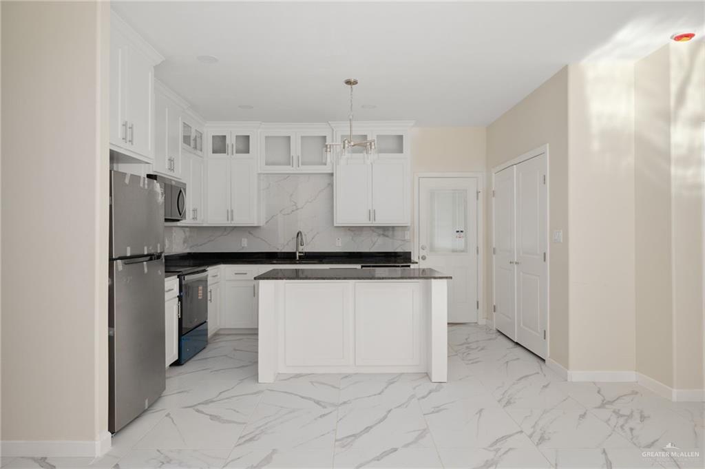 616 Mountain Road, Unit D Mission, TX 78573 - Photo 4 of 12 Kitchen with light marble finish flooring, white cabinetry, stainless steel appliances, a kitchen island, and decorative light fixtures